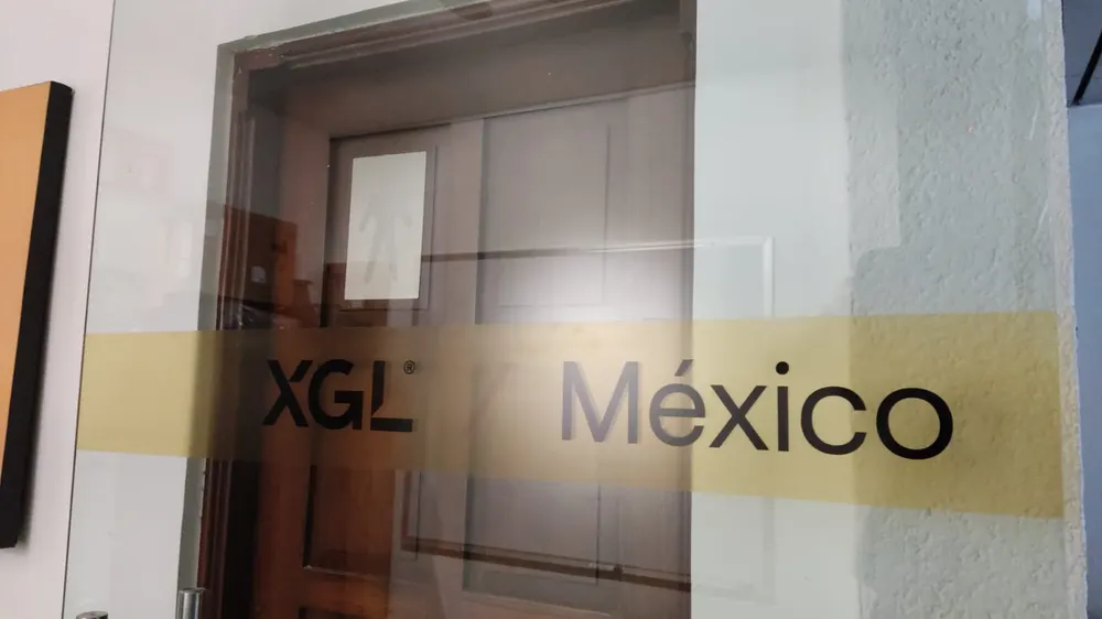Acercamiento a una franja de vinil esmerilado con el logo de XGL sobre una puerta de cristal